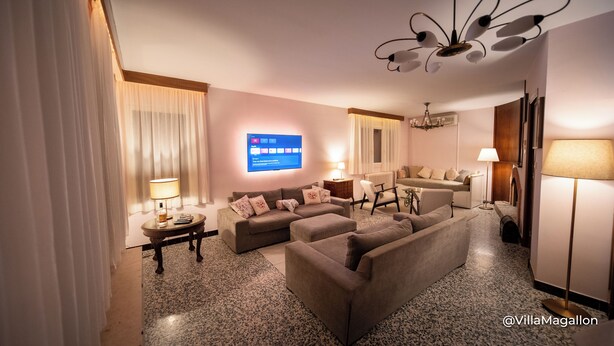 A modern hotel room with a living area featuring a sofa set, a television mounted on the wall, and a chandelier. - Villa with outbuildings close to the lake and shops. (Savines-le-Lac)