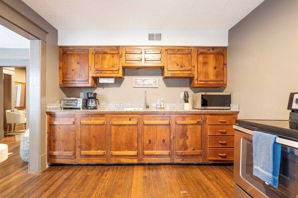 A kitchen with wooden cabinets, a microwave, a stove, and a toaster.