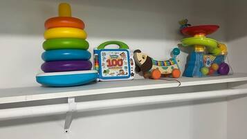 A shelf with a stack of colorful rings, a toy with a green handle, and a blue box labeled '100 WORDS BOOK'.
