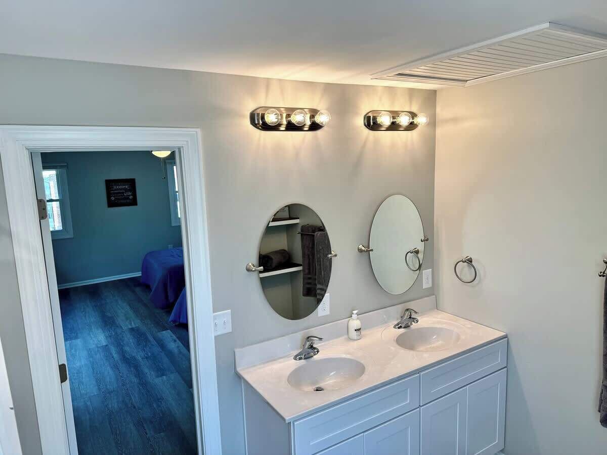 Une salle de bain avec deux lavabos, un miroir et des luminaires fixés au mur.