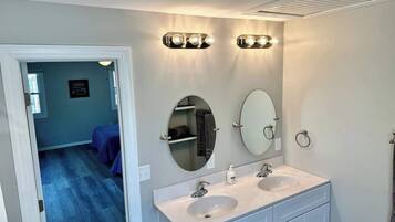 Une salle de bain avec deux lavabos, un miroir et des luminaires fixés au mur.