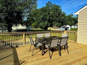 A wooden deck with a glass-top table and chairs, surrounded by a wooden railing. - Family Home on Mayo Peninsula | Deck | Sleeps 10 (Edgewater)