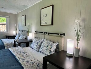 A bedroom with two beds, a bedside table, a lamp, and two framed pictures on the wall. - Family Home on Mayo Peninsula | Deck | Sleeps 10 (Edgewater)