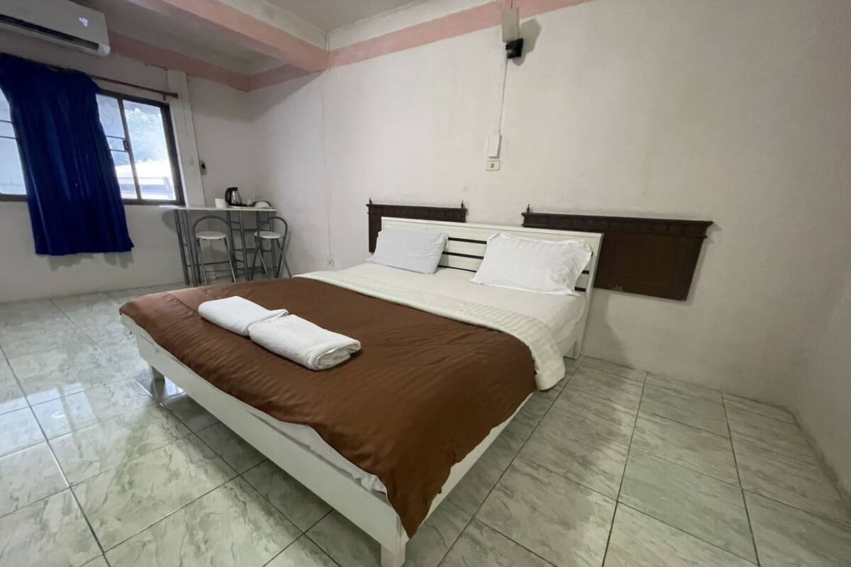 A hotel room with a bed, a desk, and a chair.