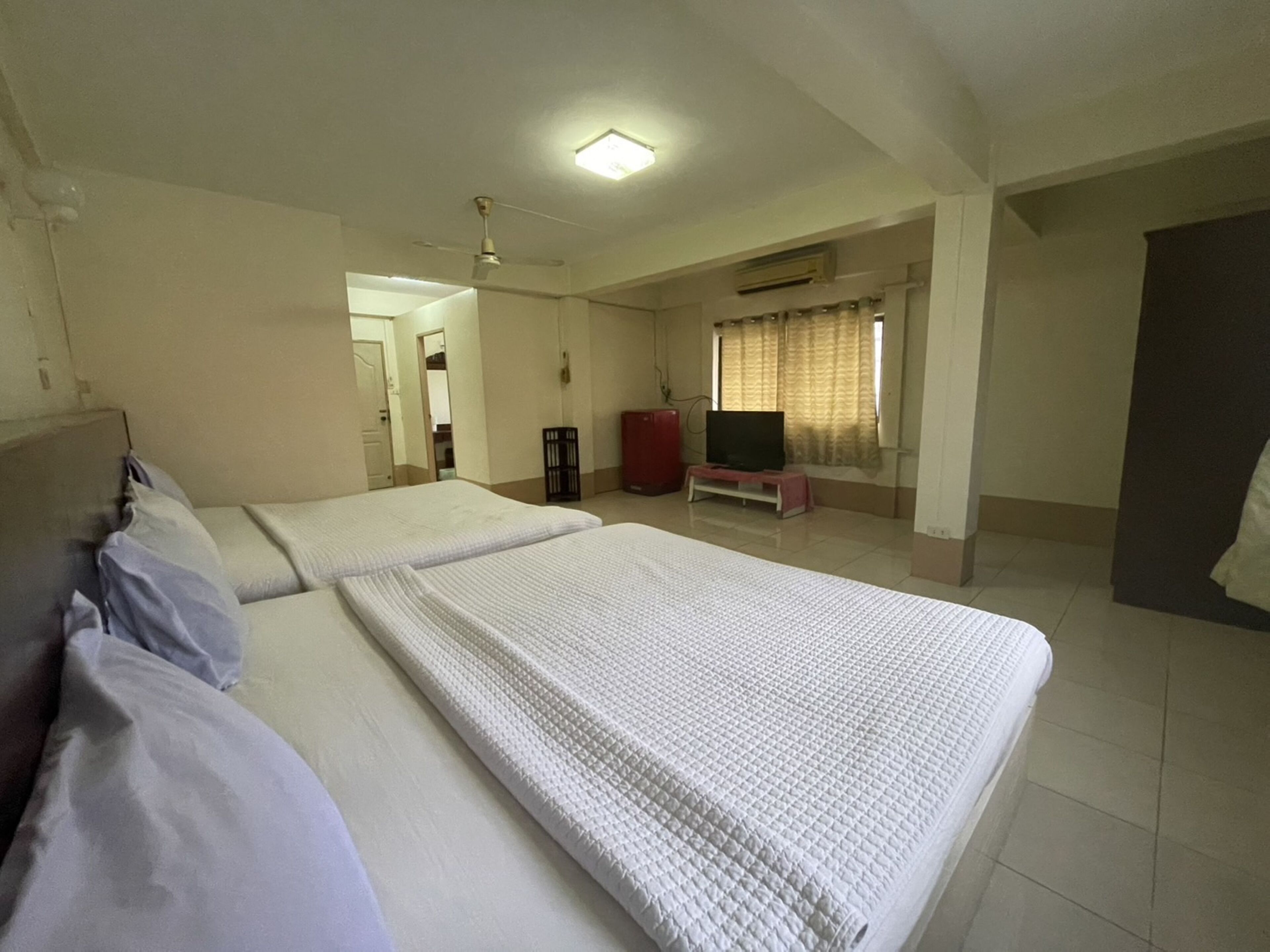 Une chambre d’hôtel avec un grand lit, une télévision et une armoire.