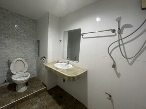 A bathroom with a toilet, sink, mirror, and shower. - OYO 75494 President Apartment (Pattaya)