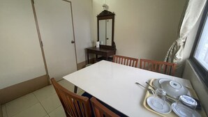 Een eethoek met een witte tafel, houten stoelen en een dienblad met borden en bestek.