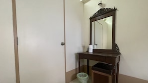 Een kamer met een deur, een spiegel, een tafeltje en een prullenbak.