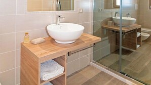 A modern bathroom with a white sink, wooden vanity, and a glass shower enclosure. - MOLAROTTO CAMERE CON ANGOLO COTTURA (San Teodoro)