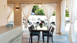 A dining area with a table and chairs, a basket, and a view of an outdoor pool and lounge chairs. - MOLAROTTO CAMERE CON ANGOLO COTTURA (San Teodoro)