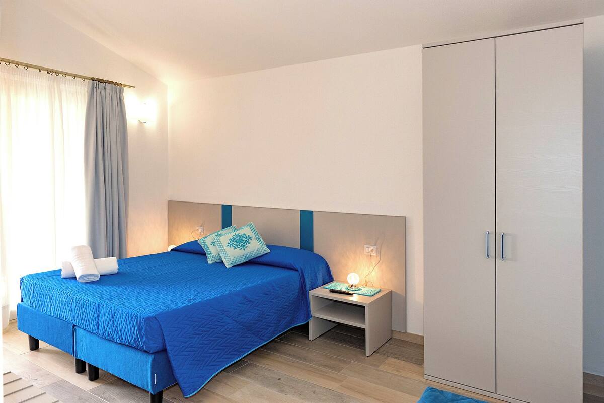 A bedroom with a bed, nightstand, and wardrobe.