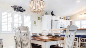 A dining area with a white table, matching chairs, and a chandelier. - Teal Tidez Ocean View Luxury Home w Crows Nest (Murrells Inlet)