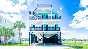 A multi-story building with balconies, a covered entrance, and a view of the surrounding area. - Teal Tidez Ocean View Luxury Home w Crows Nest (Murrells Inlet)