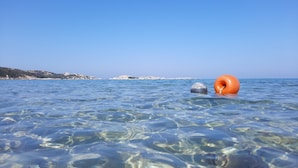 Clear shallow water with a buoy and a rocky shoreline in the background. - Bosa Marina Fronte Mare (Bosa)