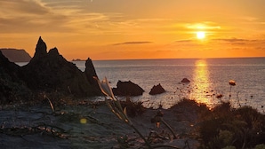 A coastal sunset with rocky formations and calm sea. - Bosa Marina Fronte Mare (Bosa)