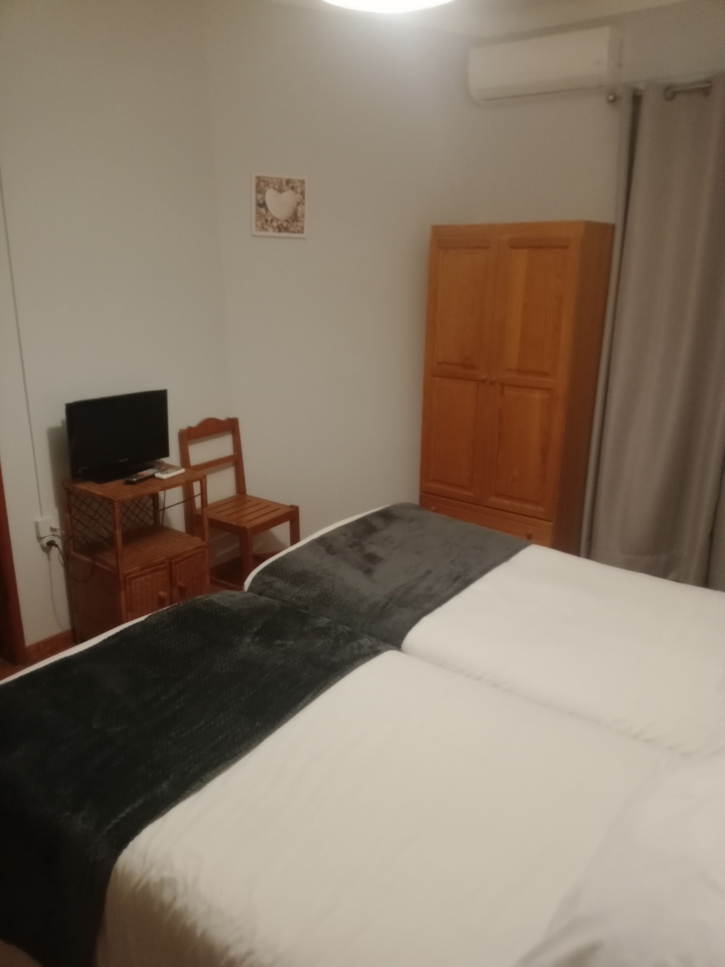 A bedroom with a bed, a desk with a television, a chair, and a wardrobe.