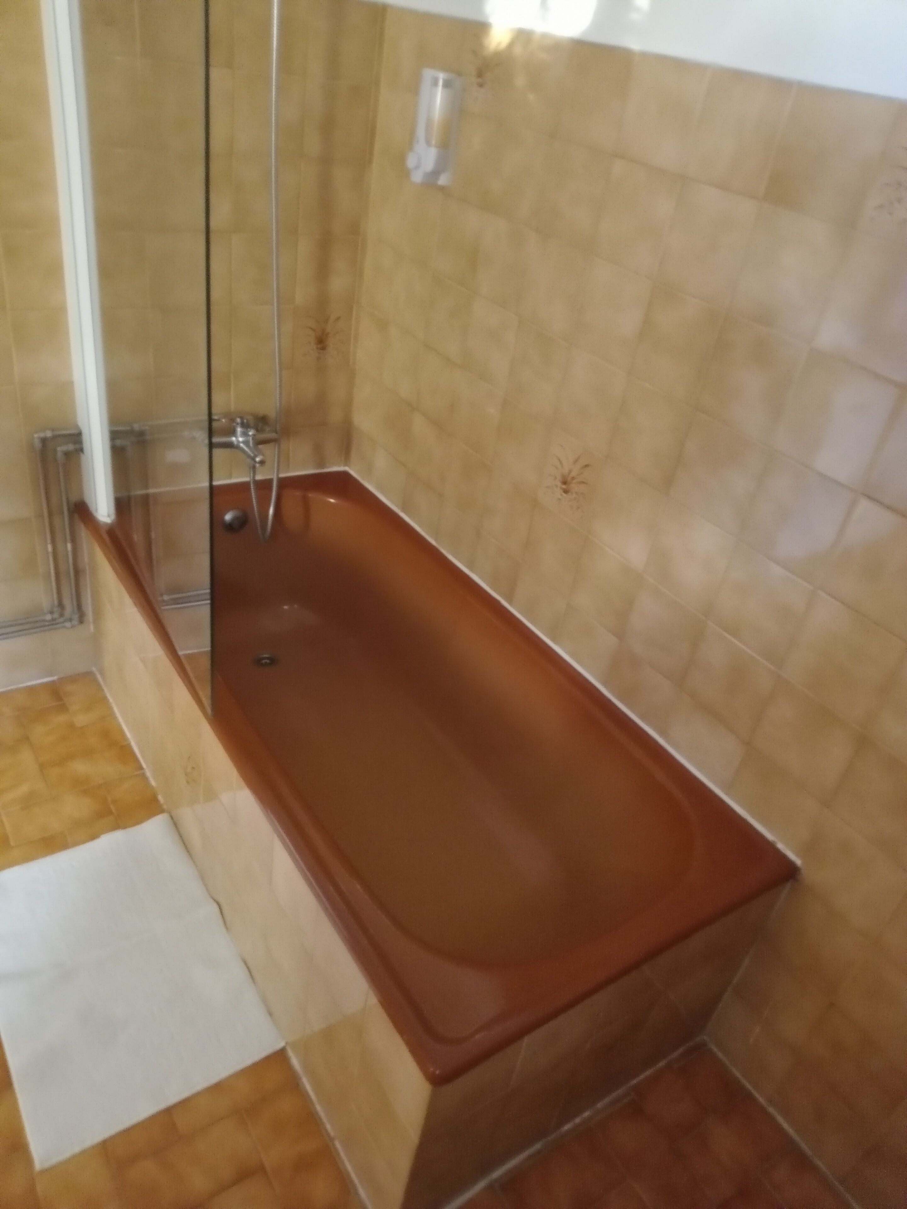 Ein Badezimmer mit einer Duschkabine, Holzboden und beige gefliesten Wänden.