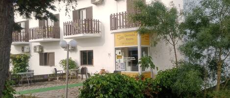 A building with balconies, a sign for 'Dormidas Rooms', and outdoor seating.