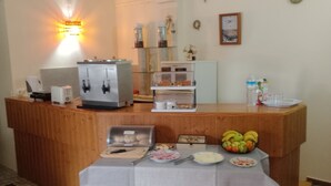 A reception area with a coffee machine, tea station, and a fruit bowl on a table.