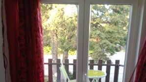 A room with a sliding glass door leading to an outdoor patio with a white chair and a small table.