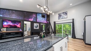 Une cuisine moderne dotée d’un grand îlot central, d’un four encastré et d’un lave-vaisselle. Une grande fenêtre offre une vue sur l’extérieur.