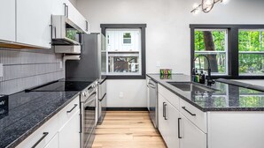 Une cuisine moderne avec des armoires blanches, un comptoir noir et un plancher en bois.