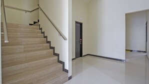 A staircase with wooden steps and a metal handrail, leading to a door with a small window. - Hotel O Irma's Residence (Blitar)
