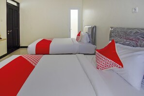 Habitación de hotel con dos camas, cada una con ropa de cama blanca y detalles en rojo. Se observa una puerta a la izquierda y una ventana a la derecha.