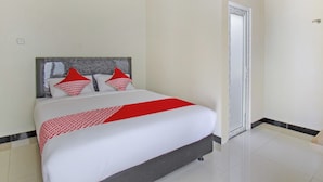 A neatly made bed with a white and red bedspread, a grey headboard, and red pillows. - Hotel O Irma's Residence (Blitar)