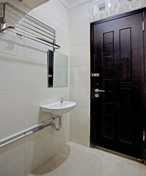 Un baño con lavamanos blanco, un espejo, un perchero para toallas y una puerta negra.