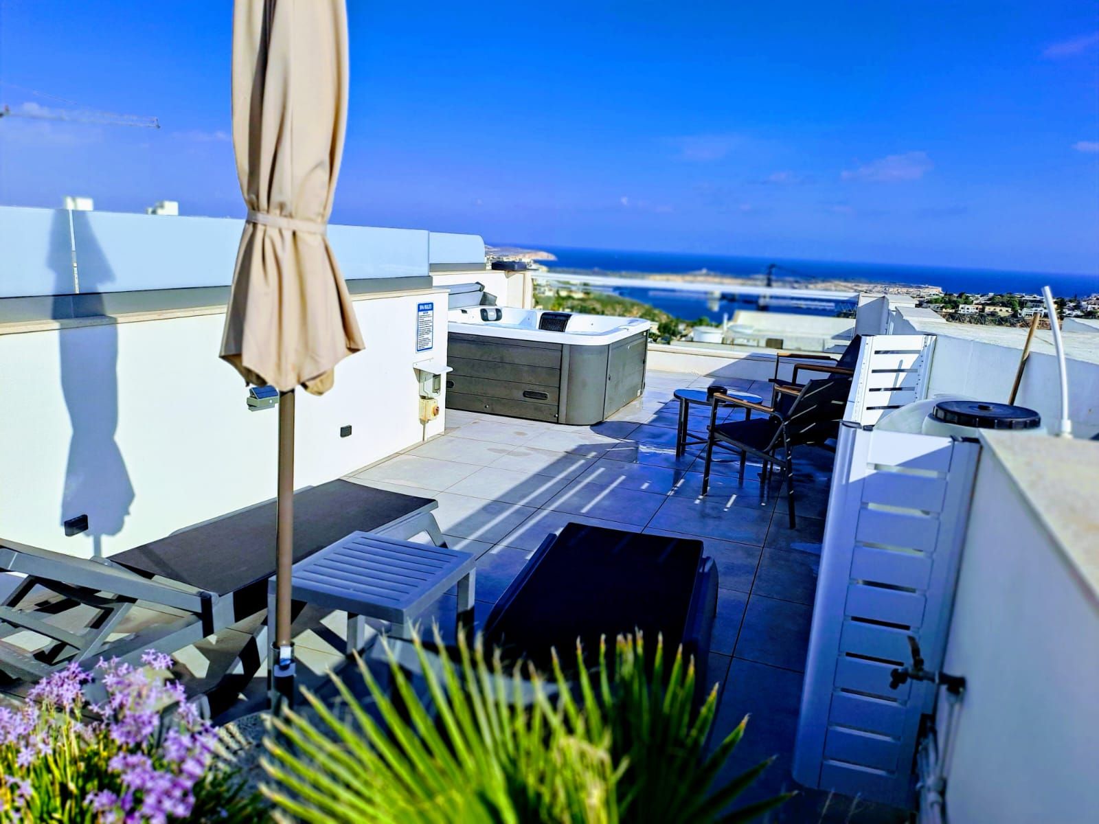Une terrasse sur le toit avec des sièges extérieurs, un barbecue et une vue sur la mer.