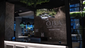A reception area with a reception desk, a wall with greenery, and a sign that reads "O.B.A Luxury Boutique Reception". - OBA LUXURY BOUTIQUE (Constanta)