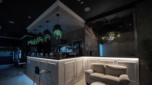 A modern bar area with a counter, bar stools, and a sofa. - OBA LUXURY BOUTIQUE (Constanta)