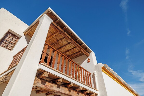 Un bâtiment doté d’un balcon en bois et d’une façade blanche.