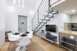 A modern kitchen with a built-in stove, a large window, and a dining area with a white table and chairs. - Easylife - Elegance and Comfort in Loreto (Milano)