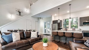A modern kitchen with stainless steel appliances, a bar area, and a dining space with bar stools. - Douglas Lake Life and Pigeon Forge Adventures (Sevierville)