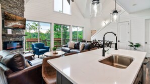 A spacious kitchen with a large island, a stone fireplace, and a dining area with outdoor seating. - Douglas Lake Life and Pigeon Forge Adventures (Sevierville)