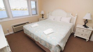 Une chambre à coucher avec un lit, deux tables de chevet avec des lampes, un radiateur et une fenêtre avec des stores.
