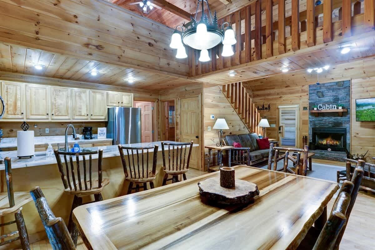 L’intérieur d’une cabane comprenant un coin repas, une cuisine et une cheminée.