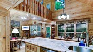 Una cocina tipo cabaña con paredes de madera, encimera de mármol y lavavajillas integrado.