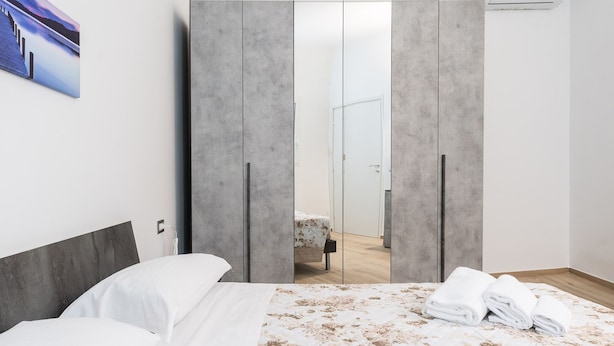 Une chambre d’hôtel moderne avec un grand lit, une armoire et une vue sur le couloir.