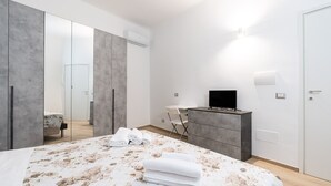 Une chambre moderne avec un grand lit, un téléviseur à écran plat, une commode et une armoire.