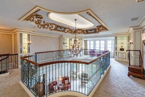 Un intérieur somptueux, avec un plafond haut, des décorations élaborées, un balcon doté d’une balustrade et un lustre.