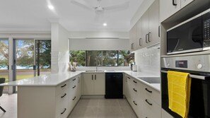 A modern kitchen with white cabinetry, a black dishwasher, and a Samsung oven. - Luxury Home Riverside Retreat (Annandale)
