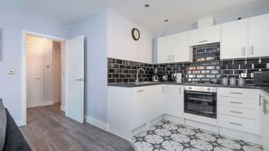 Une cuisine moderne avec des meubles blancs, un dosseret carrelé noir et blanc et un sol à motifs noir et blanc.