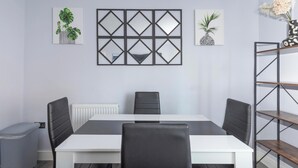 Une salle de réunion moderne avec une table blanche, des chaises noires et une étagère à motifs noirs et blancs.