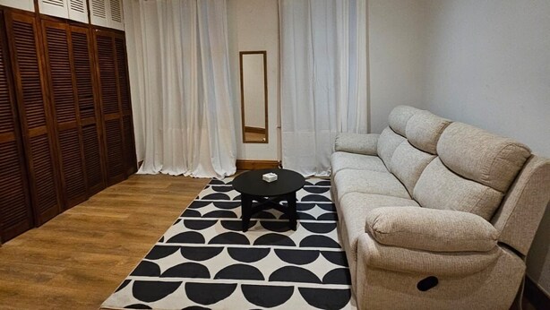 A living room with a beige sofa, a black coffee table, and a patterned rug. - Primely Located 1-bed Apartment in Brighton (Brighton)