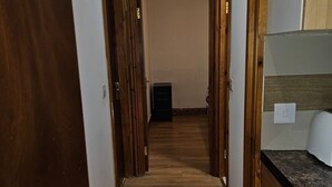 A hallway with wooden flooring, a black cabinet, and a white wall with a light switch. - Primely Located 1-bed Apartment in Brighton (Brighton)