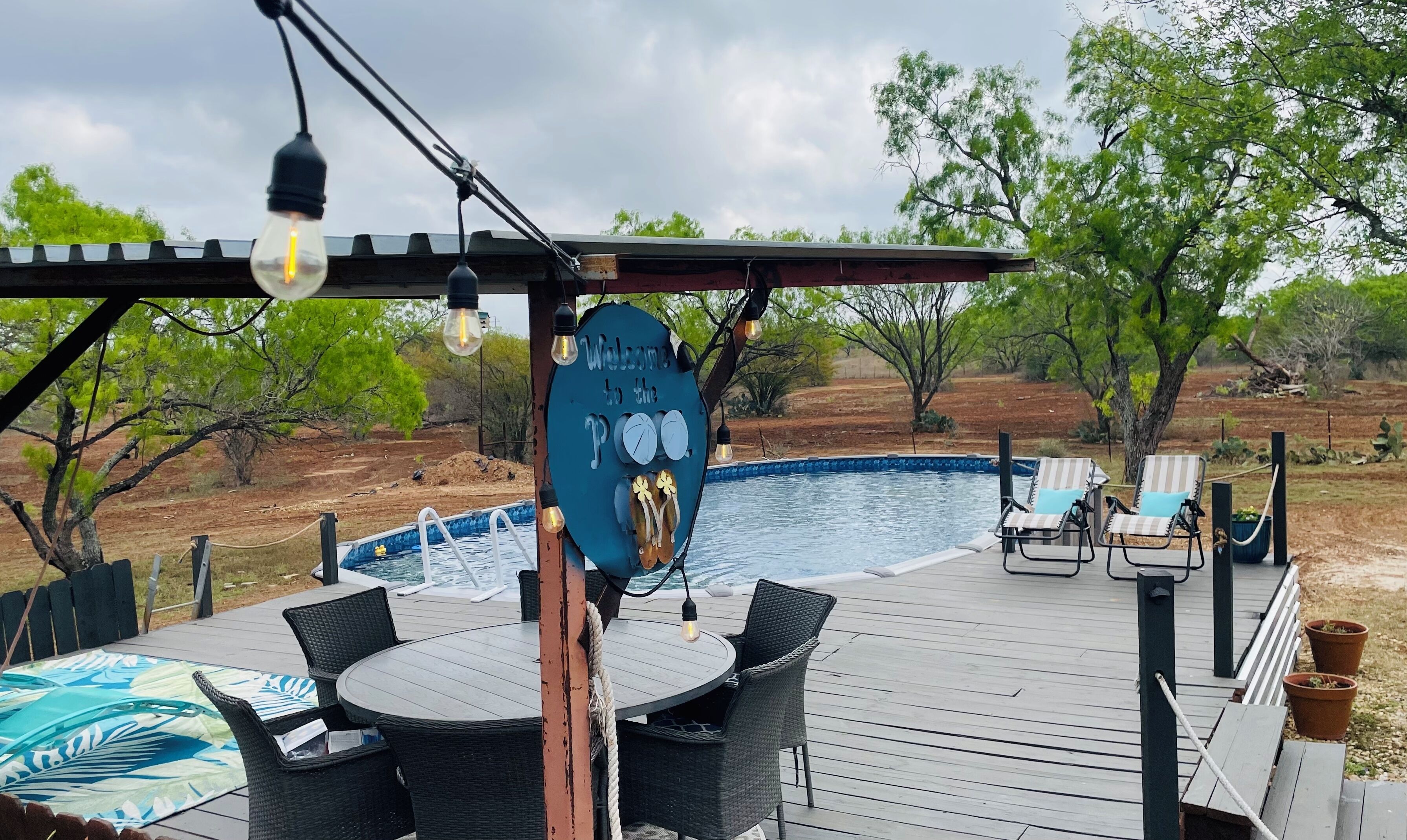 Un espace aménagé au bord de la piscine, comprenant une pergola, des chaises longues et une table.