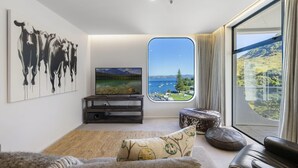 A modern living room with a large window offering a scenic view of a lake and mountains.